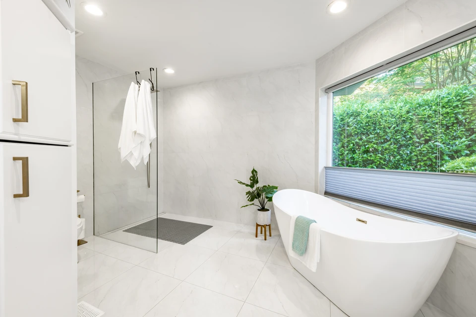 Plombier professionnel travaillant sous un lavabo de salle de bain, utilisant une clé à molette rouge pour réparer ou installer la robinetterie