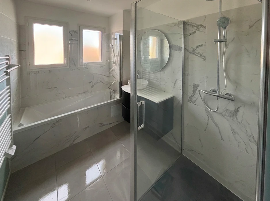 Salle de bain moderne rénovée avec douche à l'italienne, paroi en verre dépoli, meuble vasque suspendu rouge bordeaux avec tiroirs, plan vasque céramique blanc, mitigeur chromé monotrou, colonne de rangement assortie, miroir armoire avec éclairage LED, carrelage mural effet béton et marbre, receveur de douche extra-plat