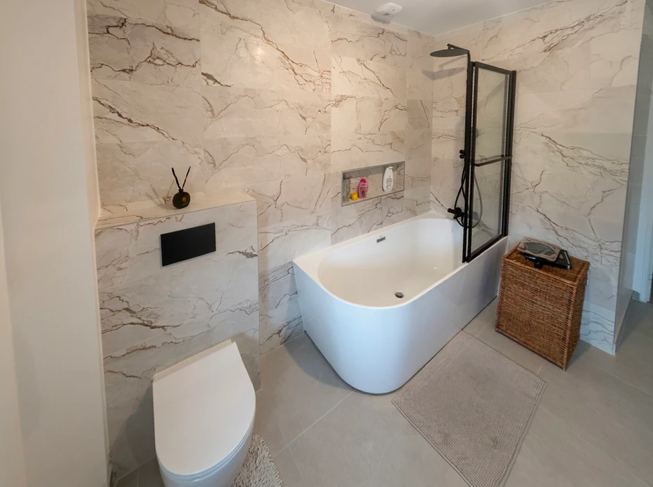 Salle de bain moderne avec baignoire encastrée, douche à l'italienne avec paroi en verre trempé, vasque à poser sur meuble suspendu gris, miroir rond