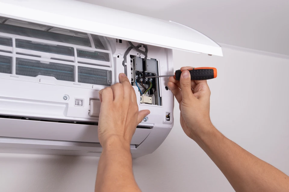 Technicien HVAC en uniforme vert travaillant sur système de chauffage/climatisation dans intérieur résidentiel