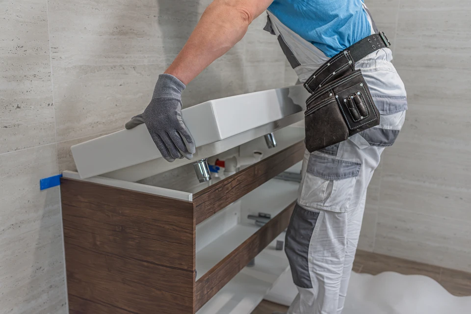 Travailleur masculin réparant la tête de douche du bain en métal et faisant des travaux de plomberie pendant qu'il travaillait à la rénovation de la maison